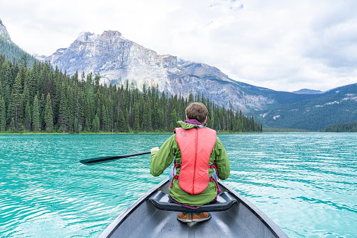 Tandem Kayak rider on a lake and mountains in the background in Canada